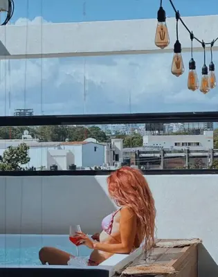 a woman sitting on a table with a glass of wine at Studio 27 in Santo Domingo