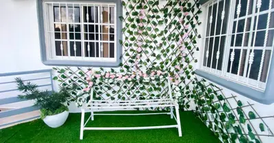 a white chair sitting in the grass next to two windows at Quiet Apartment, 3 Minutes From The Beach, 24H Security, Excellent Internet in San Felipe de Puerto Plata