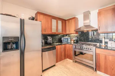 a kitchen with wooden cabinets and a stainless steel refrigerator at Golf View Apt at Casa De Campo in El Infiernito