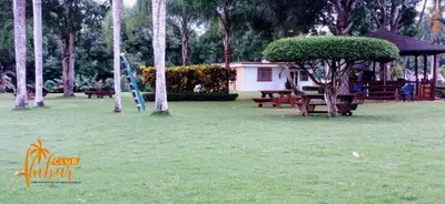 a park with picnic tables and a tree in the grass at Villas Club Ámbar in Cacique