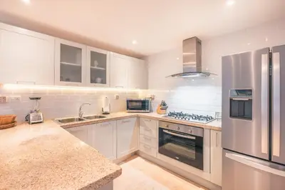 a kitchen with white cabinets and a stainless steel refrigerator at 3BR Beachfront townhouse at Puerto Bahia in Santa Bárbara de Samaná