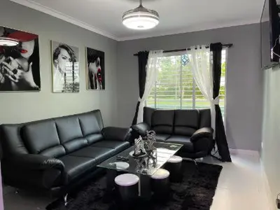 a living room with black leather couches and a table at Residencial PALMA REAL in Santiago de los Caballeros