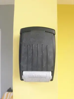 a black soap dispenser on a yellow wall at Residencial PALMA REAL in Santiago de los Caballeros