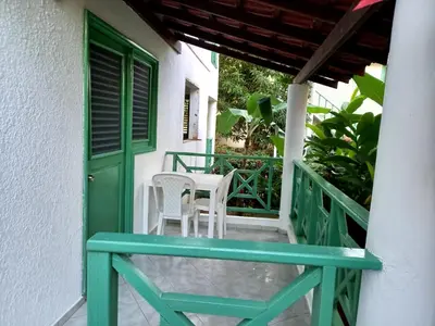 a porch with a green door and white chairs at Residence Nord Est in Las Terrenas