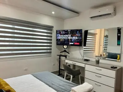 a bedroom with a bed and a desk and a television at SOHA SUITES II in Santiago de los Caballeros