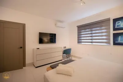 a bedroom with a bed and a tv and a window at SOHA PANORAMA in Santiago de los Caballeros