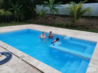 a group of three people in a swimming pool at Piscalonga Hotel Restaurant Cozy Family Operated in San Lorenzo de Guayubín