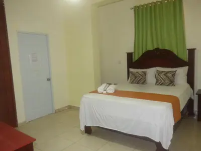 a bedroom with a bed with a green curtain at Hotel Enrique I Gazcue, Bed and Breakfast in Santo Domingo