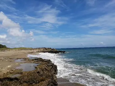 a beach with rocks and the ocean on a cloudy day at Hermoso apartamento de playa en perla marina Sosua - Cabarete in Sosúa