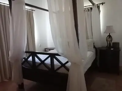 a bedroom with a bed with white curtains at Hermoso apartamento de playa en perla marina Sosua - Cabarete in Sosúa