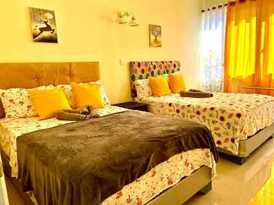 a bedroom with two beds with yellow and orange pillows at Hotel María Bonita Higüey, Apartments in Higuey