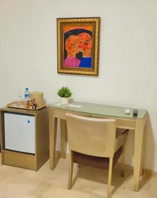 a desk with a painting on the wall and a table and chair at Naranjo Hotel Boutique in Higuey