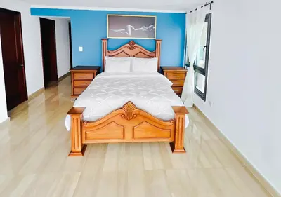 a bedroom with a wooden bed and a blue wall at Exclusive 3 BDR, Gym & Pool, SeaView, Luxury Tower in Santo Domingo