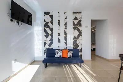 a living room with a blue couch and a tv at EDMA APARTAHOTEL in Santa Bárbara de Samaná