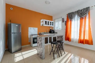 a kitchen with orange walls and a stainless steel refrigerator at EDMA APARTAHOTEL in Santa Bárbara de Samaná