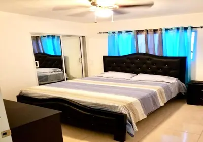 a bedroom with a large bed with blue curtains at Acogedor apartment , seguridad las 24 horas , Cibao International Airport 8 minutos, Centro de Santiago 10 Minutos , Tamboril la capital mundial del cigarro 10 minutos in Licey al Medio