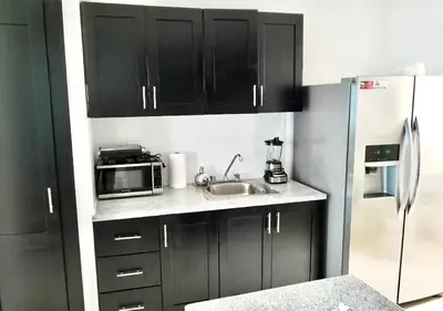 a kitchen with black cabinets and a sink and a refrigerator at Acogedor apartment , seguridad las 24 horas , Cibao International Airport 8 minutos, Centro de Santiago 10 Minutos , Tamboril la capital mundial del cigarro 10 minutos in Licey al Medio