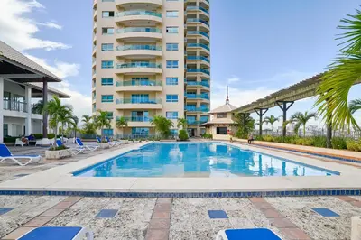 a swimming pool in front of a tall building at Exquisite Oceanfront Suite in Santo Domingo