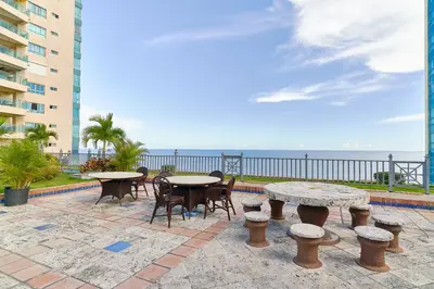 a patio with tables and chairs and the ocean at Exquisite Oceanfront Suite in Santo Domingo