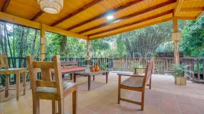 a patio with a table and chairs under a wooden pergola at El Yaguacil villa in Jarabacoa