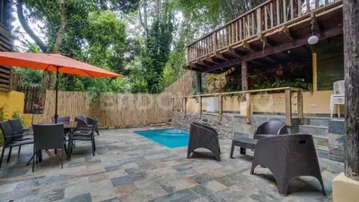 a patio with a table and chairs and an umbrella at El Yaguacil villa in Jarabacoa