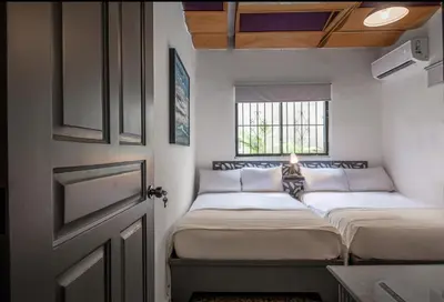 two beds in a small room with a window at PH 19 Guesthouse Hotel in Gazcue in Santo Domingo