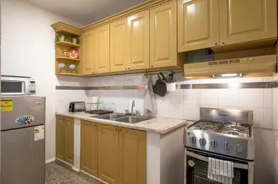 a kitchen with yellow cabinets and a sink and a refrigerator at PH 19 Guesthouse Hotel in Gazcue in Santo Domingo