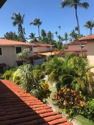 a garden in front of a house with palm trees at La Cortesana Cozy Apt Steps to the Beach in Las Terrenas