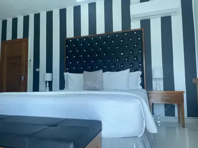 a bedroom with a large white bed and a striped wall at Gaia Residence Deluxe in San Felipe de Puerto Plata