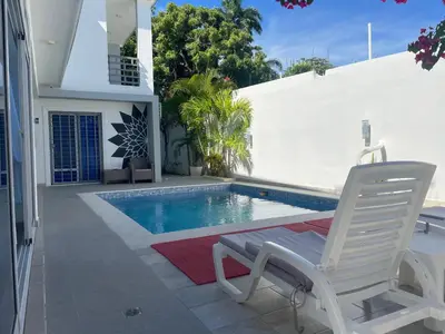 a swimming pool with two chairs next to a house at Gaia Residence Deluxe in San Felipe de Puerto Plata