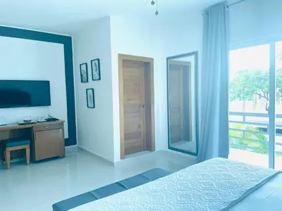 a bedroom with a bed and a television and a balcony at Gaia Residence Deluxe in San Felipe de Puerto Plata