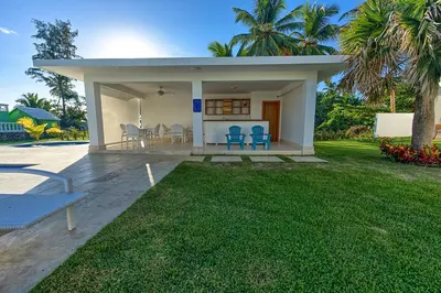 a small white house with blue chairs and a yard at Amazing ocean view apartment with grand pool in Cabarete