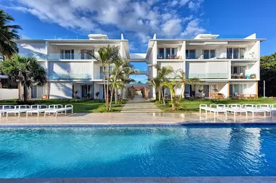 a large white house with a swimming pool in front of it at Amazing ocean view apartment with grand pool in Cabarete