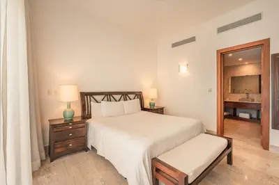 a white bedroom with a bed and a mirror at Go away to this charming apt at Sublime w private jacuzzi included in Las Terrenas
