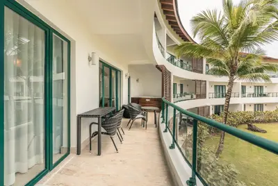 a balcony with chairs and a table and a palm tree at Go away to this charming apt at Sublime w private jacuzzi included in Las Terrenas