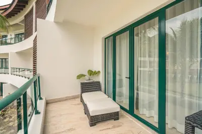 a balcony with a chair and glass doors at Go away to this charming apt at Sublime w private jacuzzi included in Las Terrenas