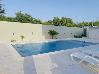 a swimming pool with two white chairs next to a wall at 5 Star Villa minutes from Airport and Beaches in Sosúa