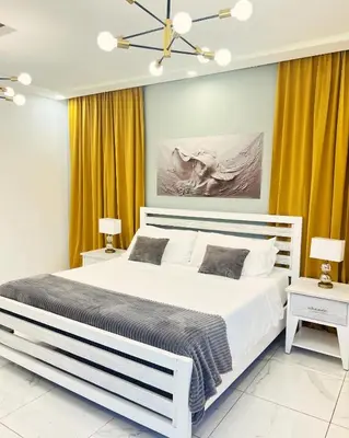 a bedroom with a large white bed and yellow curtains at 5 Star Villa minutes from Airport and Beaches in Sosúa