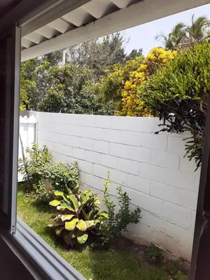 a window view of a backyard with a white brick wall at Apartamento Hogareño in Jarabacoa
