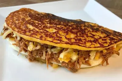 a sandwich with cheese and meat on a white plate at Apartamento Hogareño in Jarabacoa