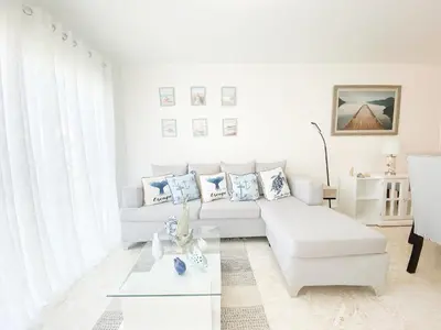 a white living room with a couch and a table at Xeliter Green One Playa Dorada in San Felipe de Puerto Plata