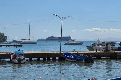 a dock with boats in the water with a cruise ship at Indy's Best Bay FrontView in Samana. in Santa Bárbara de Samaná