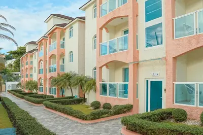 an apartment building with a blue door and bushes at Ria Hotel in San Felipe de Puerto Plata