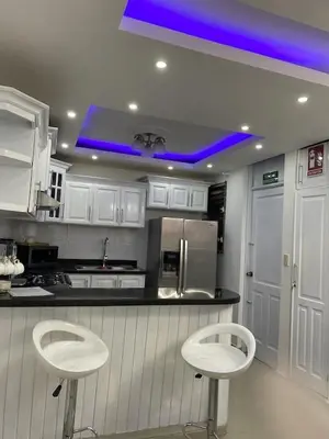 a kitchen with two white stools and a blue light at Sweet Home in Santiago de los Caballeros