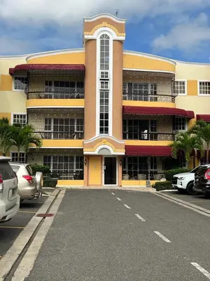 a large building with cars parked in a parking lot at Sweet Home in Santiago de los Caballeros