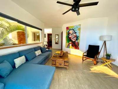 a living room with a blue couch and a painting at Panoramic Views Two Decks 1st Row Ocean Kite Beach in Cabarete