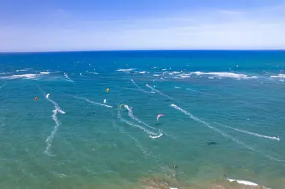 a group of people kite surfing in the ocean at Kite Beach Oceanfront Two Bedroom Patio and Garden in Cabarete