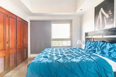 a bedroom with a blue bed and a window at Luxurious 2BDR condo located in Prestigious Tower. in Santo Domingo