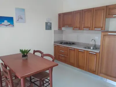 a kitchen with wooden cabinets and a table and a sink at CoralK Apartments Sosúa in Sosúa