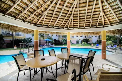 a patio with tables and chairs next to a swimming pool at Ocean Dream Art Deco Studio w/balcony in Cabarete